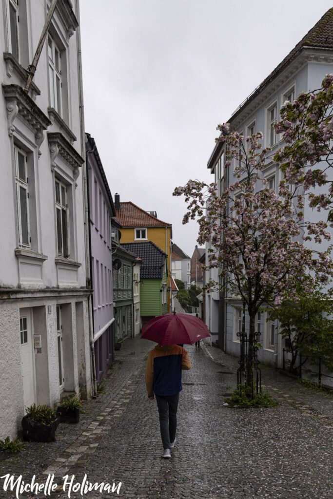 Person in a raincoat with an umbrella walking the streets of Bergen, Norway